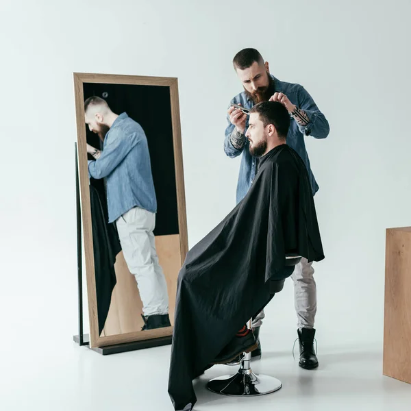 Боковой вид парикмахера бритья волосы клиента в парикмахерской — стоковое фото
