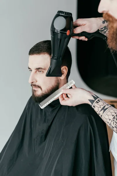 Imagen recortada de barba de cliente de secado peluquero en la barbería - foto de stock