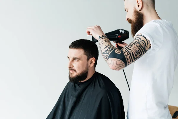 Barber drying customer hair at barbershop isolated on white — Stock Photo