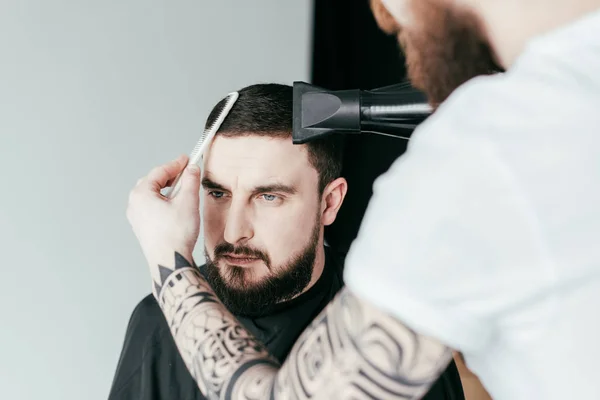 Cropped image of barber drying customer hair at barbershop — Stock Photo
