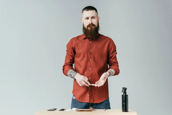 Guapo peluquero sosteniendo tijeras y mirando a la cámara aislada en blanco - foto de stock