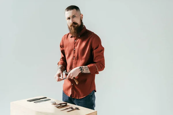 Бородатый красивый парикмахер рядом со столом с оборудованием изолированы на белом — стоковое фото