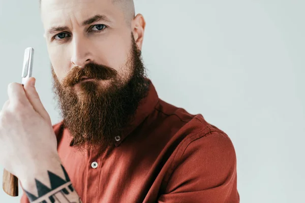 Портрет бородатого красивого парикмахера, держащего бритву изолированной на белом — стоковое фото