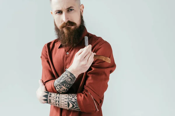 Bearded serious barber holding razor isolated on white — Stock Photo