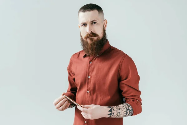 Bearded handsome barber holding razor and looking at camera isolated on white — Stock Photo