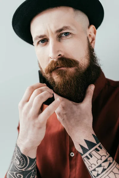 Bearded handsome man combing beard and looking at camera isolated on white — Stock Photo