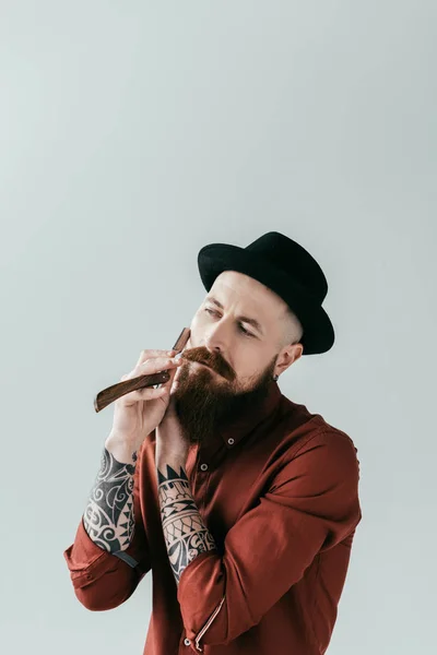 Bearded tattooed man shaving beard with razor isolated on white — Stock Photo