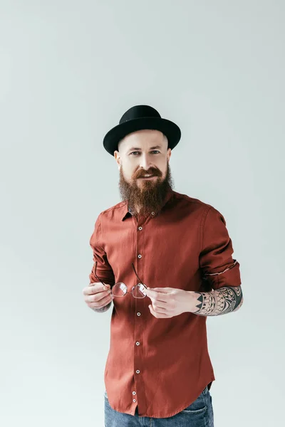 Smiling bearded man holding glasses and looking at camera isolated on white — Stock Photo