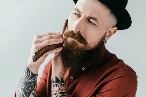 Бородатый красивый мужчина бреет бороду с бритвой изолированы на белом — стоковое фото