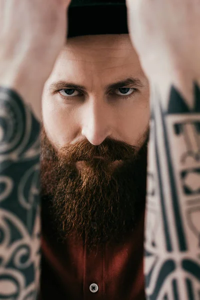 Barbudo hombre tatuado mostrando gesto de bloque y mirando a la cámara - foto de stock