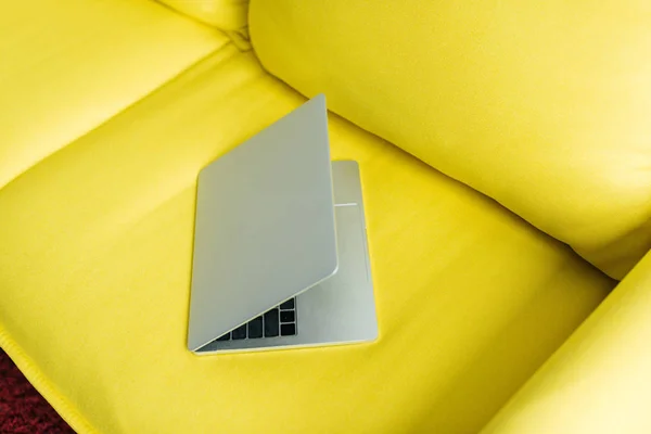 Laptop semi-fechado no sofá de couro amarelo, concepção minimalista — Fotografia de Stock