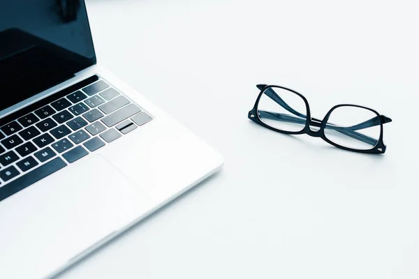 Laptop mit leerem Bildschirm und Brille daneben, minimalistisches Konzept — Stockfoto