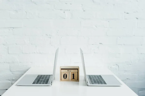 Calendrier en bois entre deux ordinateurs portables sur table blanche — Photo de stock