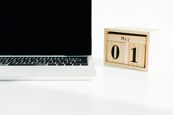 Ordenador portátil y calendario de madera en la superficie blanca - foto de stock