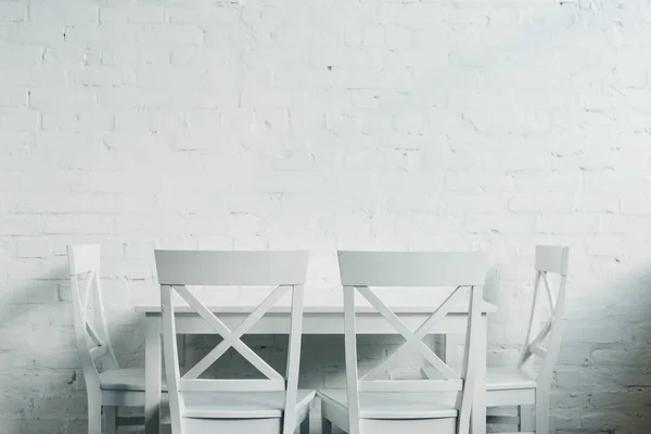 Интерьер столовой с деревянным столом и стульями перед кирпичной стеной — стоковое фото