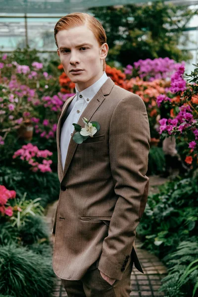 Portrait of pensive stylish man with red hair in suit standing glasshouse — Stock Photo