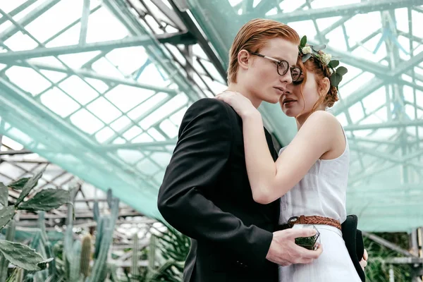 Porträt romantischer Braut und Bräutigam, die sich im Gewächshaus umarmen — Stockfoto