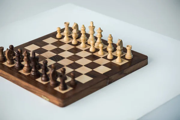 Vista de ángulo alto de tablero de ajedrez con piezas de queso conjunto para el nuevo juego aislado en blanco - foto de stock