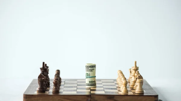 Placa de xadrez com dinheiro e peças de xadrez isoladas em branco — Fotografia de Stock