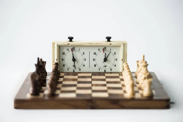 Reloj de ajedrez y tablero de ajedrez con figuras fijadas para el nuevo juego aislado en blanco - foto de stock