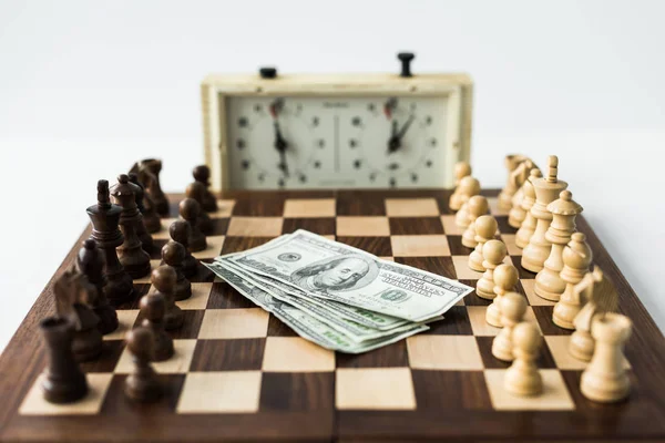 Chess board with cash and figures near chess clock isolated on white — Stock Photo