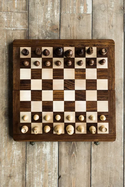 Vue du dessus de l'échiquier avec des pièces d'échecs réglées pour le nouveau jeu sur la surface en bois — Photo de stock