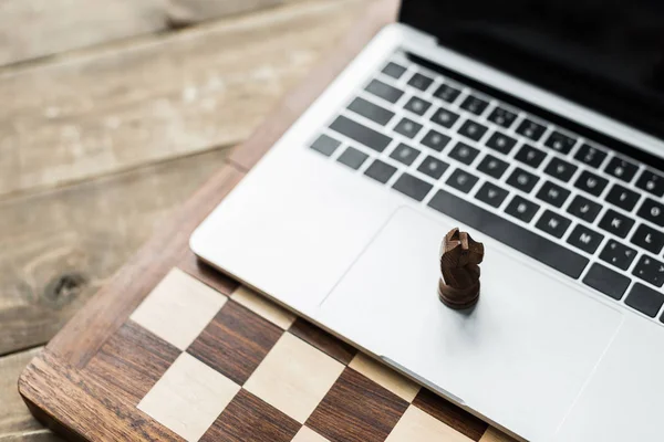 Close up of chess board and laptop with chess figure of knight — Stock Photo