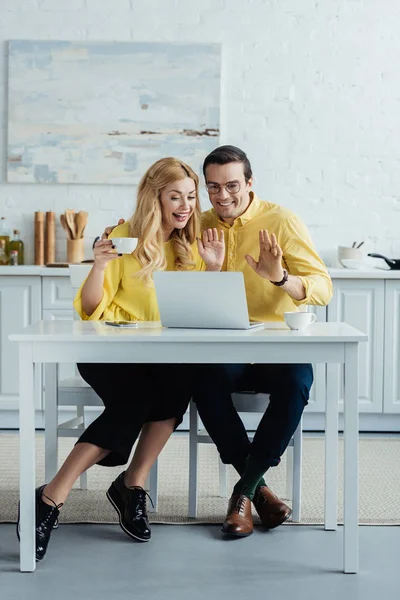 Happy man and woman drinking coffee and looking at laptop screen — Stock Photo