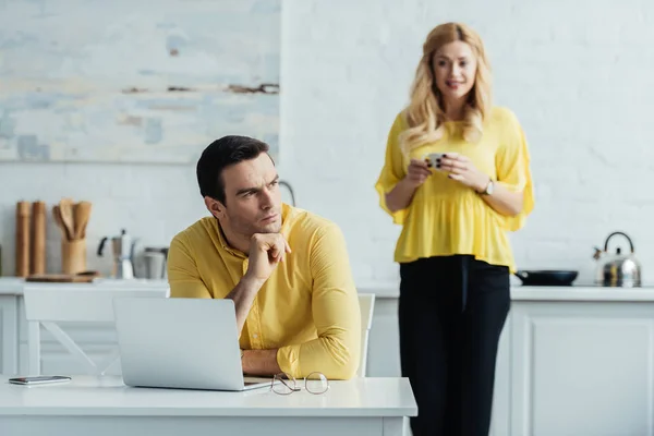 Man sitting by table with laptop in front of woman drinking coffee — Stock Photo