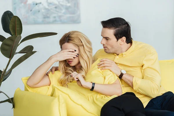 Hombre hablando con su triste novia en el sofá en la sala de luz - foto de stock