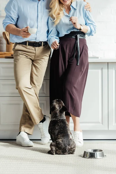 French bulldog puppy sitting on floor by owners — Stock Photo