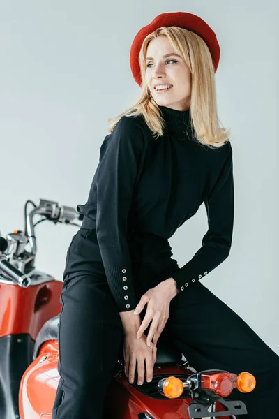 Attractive young woman in red beret posing by vintage scooter isolated on grey — Stock Photo