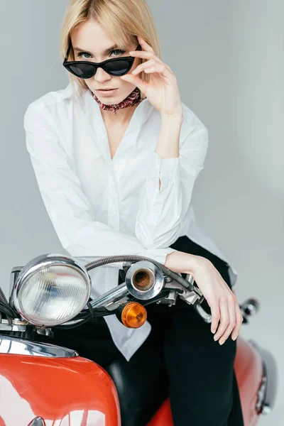 Elegante bella donna in camicia bianca in posa su scooter rosso isolato su grigio — Foto stock