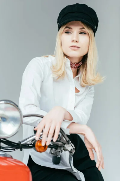 Stylish pretty woman in white shirt posing on red scooter isolated on grey — Stock Photo