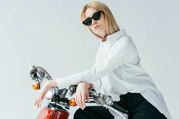 Привлекательная молодая женщина в солнечных очках на винтажном скутере, изолированном на сером — стоковое фото