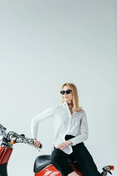 Stylish blonde girl sitting on retro scooter isolated on white — Stock Photo