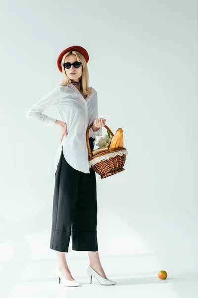 Attractive young girl carrying basket with bread and flowers — Stock Photo