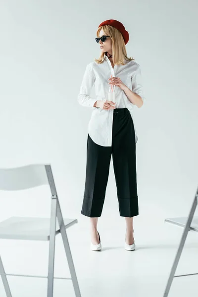 Elegante bella donna in bianco e nero vestiti in piedi di fronte a sedie — Foto stock