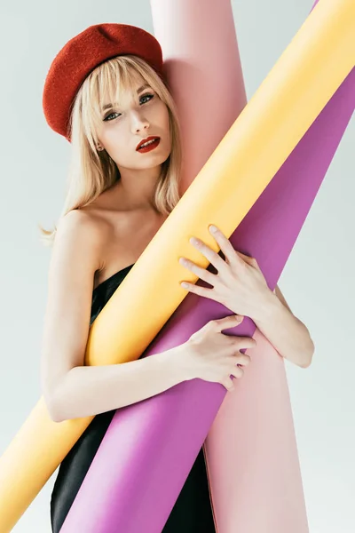 Attractive young woman holding colorful paper rolls isolated on grey — Stock Photo