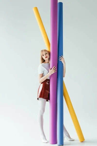 Fashionable blonde girl carrying colorful paper rolls — Stock Photo