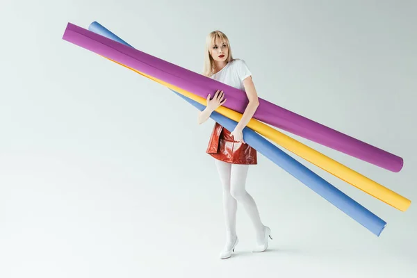 Fille blonde à la mode portant des rouleaux de papier colorés — Photo de stock