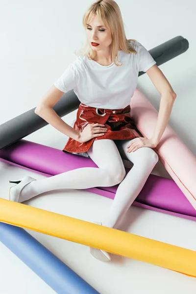 Attractive young woman posing among colorful paper rolls — Stock Photo