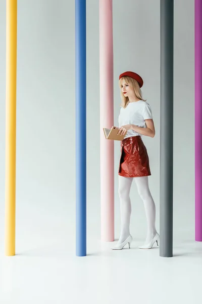 Stylish pretty woman posing by colorful pillars — Stock Photo