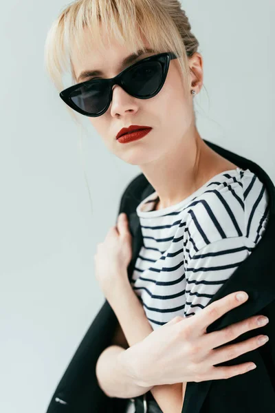 Jolie jeune femme en lunettes de soleil avec lèvres rouges isolées sur gris — Stock Photo