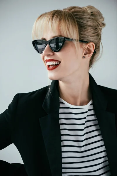 Chica rubia sonriente con gafas de sol retro aisladas en gris - foto de stock