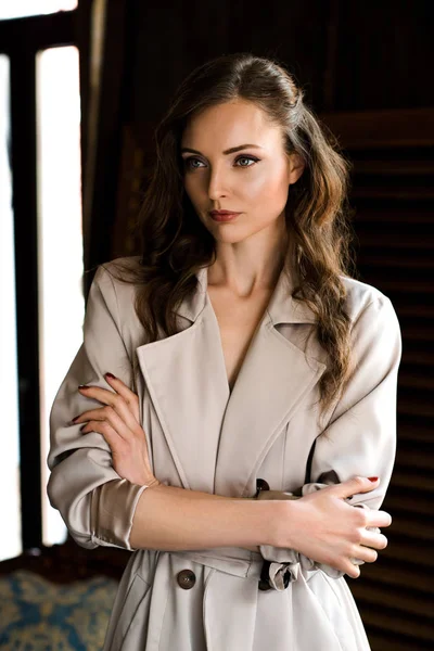 Beautiful woman in trendy trench coat with crossed arms — Stock Photo