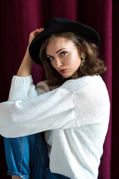 Porträt einer schönen jungen brünetten Frau mit schwarzem Hut, die in die Kamera blickt — Stockfoto