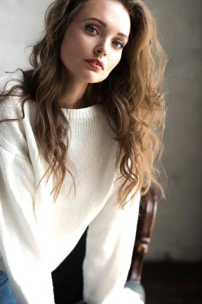 Portrait de belle jeune femme brune en pull blanc tendance regardant la caméra — Photo de stock