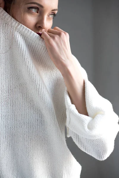 Sensual young woman taking off white sweater and looking away on grey — Stock Photo