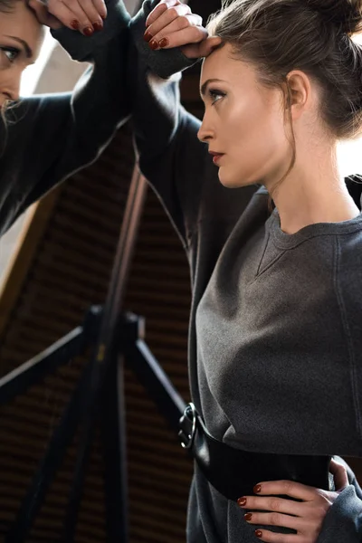 Side view of beautiful young woman in grey jumper with belt looking at mirror — Stock Photo